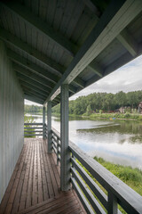 Wooden porch on the bank of the river. Middle lane, cloudy sky, calm summer weather.