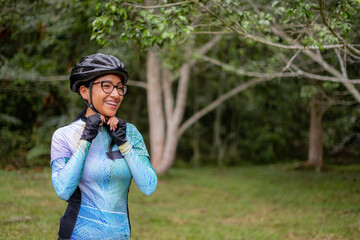 Latin young woman on a bicycle practicing cycling in the forest. Helmet placement, safety.