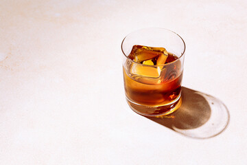 Whiskey or bourbon in a rocks glass with a big ice cube, shot with hard light and harsh shadows, bright backdrop, copy space - 490457857