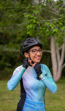 Latin young woman on a bicycle practicing cycling in the forest. Helmet placement, safety.