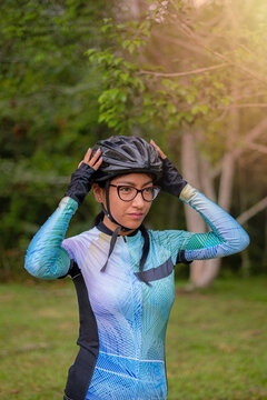Latin young woman on a bicycle practicing cycling in the forest. Helmet placement, safety.