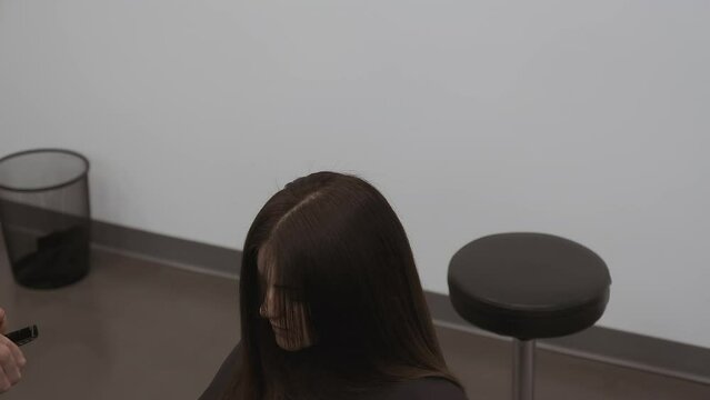 Stylist blends and texturizes long hair with angled cuts with scissors