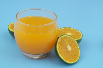 Orange juice and orange fruit slices on blue background