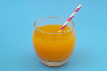 Fresh orange juice with drink straw on blue background
