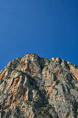 Rough rocky stones. The tops of the yellow peaks of the rocks. Red stones on a blue background. Gray rocks at high altitude. Alps top on blue sky.