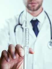 Syringe needle medical injection. Selective focus, doctor hand in blue gloves holding syringe with needle. Hospital white doctor gown, stethoscope. Syringe with flu vaccine with copy space.