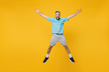 Fototapeta na wymiar Full body young fitness trainer instructor sporty man sportsman in headband blue t-shirt jump high with outstretched hands legs isolated on plain yellow background. Workout sport motivation concept.
