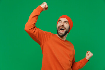 Young overjoyed happy caucasian man 20s wear orange sweatshirt hat doing winner gesture celebrate...