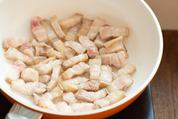 cooking spicy belly prok slice on white plate electric pan and black turner