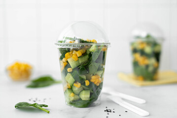 takeaway fresh vegetable salad with cucumber, spinach and corn in a plastic container