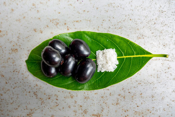 Spicy mixed salt with some black java plum fruit in the green leaves. A way to eat ripe cesium camini fruit by hand. 4k closeup video.