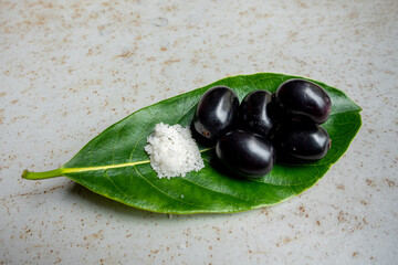 Spicy mixed salt with some black java plum fruit in the green leaves. A way to eat ripe cesium camini fruit by hand. 4k closeup video.