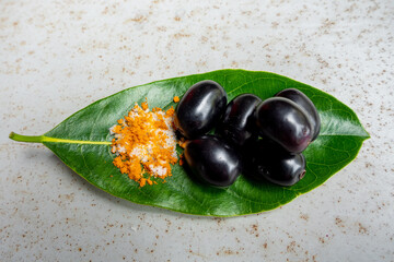 Spicy mixed salt with some black java plum fruit in the green leaves. A way to eat ripe cesium camini fruit by hand. 4k closeup video.