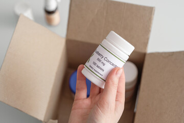 Delivery of dietary supplements. Women's hands hold a bottle of blueberry concentrate in close-up.