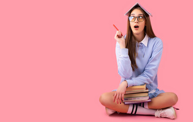 Photo of amazing young and beutiful school girl sitting isolated over pink wall background, looking aside and showing copyspace pointing, product placement.