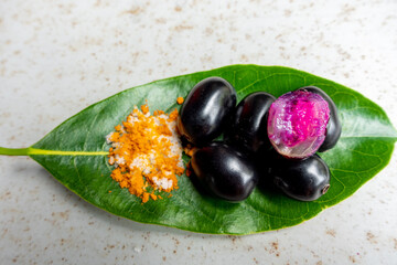 Spicy mixed salt with some black java plum fruit in the green leaves. A way to eat ripe cesium...