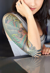 The beauty is in the detail. Cropped shot of a young tattoo artist showing off her half-sleeve...
