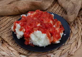 Traditional South African Pap and sous, maize meal covered in tomato and onion relish. set on...