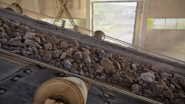 The stone ore moves along a belt conveyor. The minerals after the crushing machine are moved along the conveyor belt in the factory.