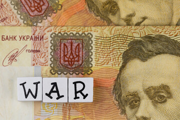 The sentence "war" composed of letters on the background of Ukrainian banknotes. Photo taken under artificial, soft light