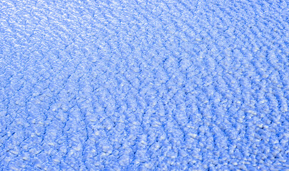 blue water waves on a sunny day with a blurred ice background