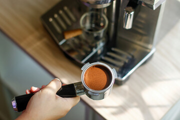 Close up of portafilter full of freshly ground coffee in hands of barista