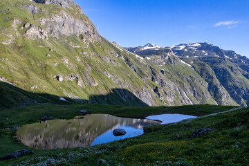 Hiking past a lake in the Aosta mountain range in late spring