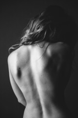Body details close-up, nude female body. Nude skin photography in black and white. Light defocus and art noise on the frames.Silhouette of a woman's bare back