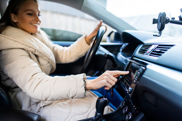 Young woman changing radio station while driving car