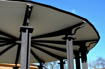 steel subtle gazebo construction with decorative beams. The roof is wooden in the shape of a flat...