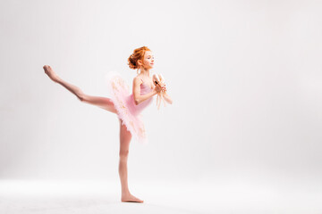 Little ballerina dancer in a pink tutu academy student posing on a white background