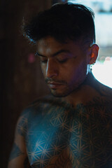 Handsome young mexican man, tattooed body. portrait, shadows