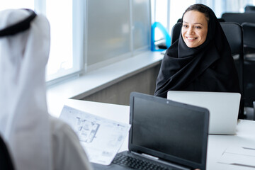 Man and woman with traditional clothes working in a business office of Dubai. Portraits of ...