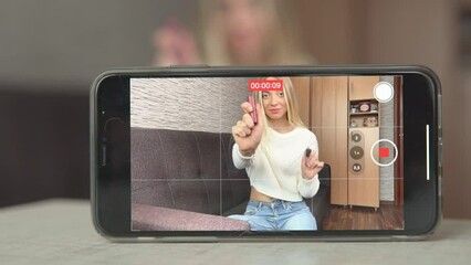 Young woman influencer, advertising and selling goods online in a live stream show. Creating video content for social media. Distant work at home studio. Beauty cosmetic shop girl recording video.