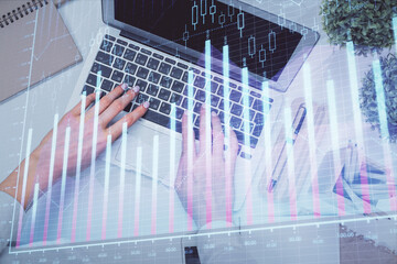 Double exposure of woman hands working on computer and forex graph hologram drawing. Top View. Financial analysis concept.