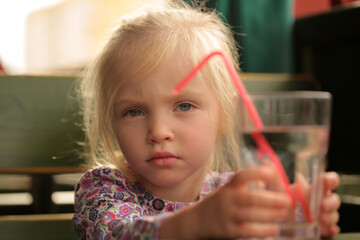 Child drinks water. Serious little girl drinks water from a glass.