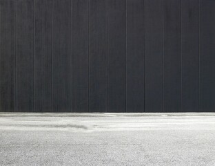 Black concrete wall with vertical blocks and an asphalt road in front. Background for copy space