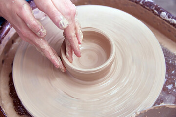 Beautiful women's hands make ceramic dishes on a spinning potter's wheel. soft focus.