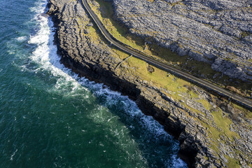Small road by a mountain in Burren, Ireland. Wild Atlantic way. Beautiful scenery with rough stone coastline. Nobody, Warm sunny day. Travel and tourism area. Aerial view. Irish landscape