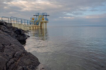 Blackrock diving board at Salthill area of Galway city, Ireland. Calm water surface of Atlantic ocean and Galway bay. Beautiful cloudy sky. Town landmark and popular tourist spot.