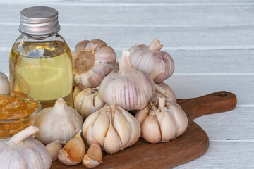 Fresh garlic bulbs are stacked on wooden cutting board.