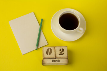 coffee with a notebook and the date of March 2 on a yellow background