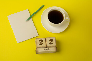 coffee with a notebook and the date of March 22 on a yellow background