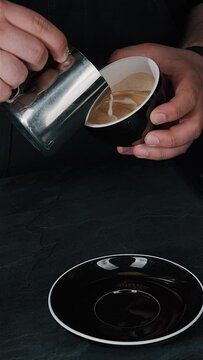 Barista pouring milk in hot coffee and making cappuccino foam in cafe close up,