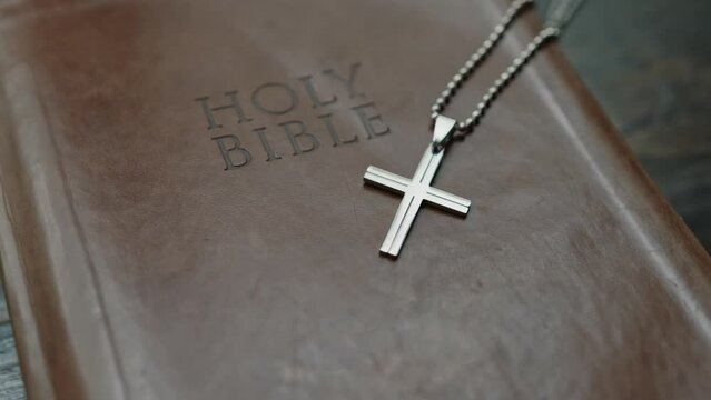 Close up of a holy bible book cover with a necklace of a cross on it, religion scriptures background