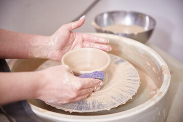 Beautiful women's hands make ceramic dishes on a spinning potter's wheel. soft focus.