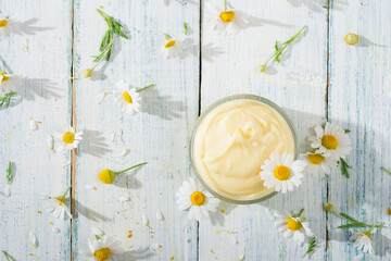 chamomile flowers and baby cream on white wooden table, directly above