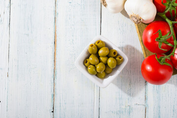 fresh tomato, garlic, olive, uncooked tagliatelle pasta on white wooden table, top view