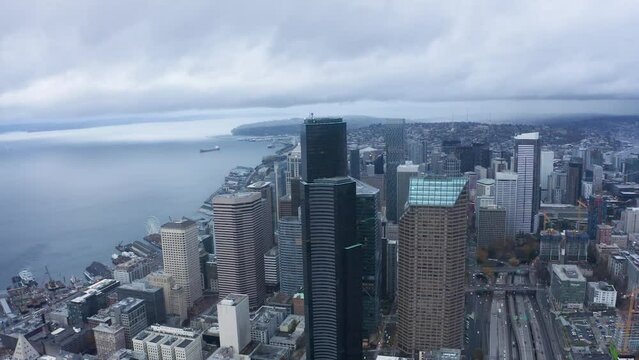Wide aerial shot pulling away from Seattle's looming skyscrapers on a wet and cloudy day.