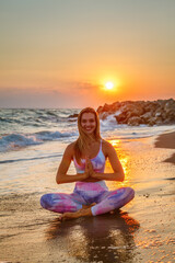 Fototapeta na wymiar Happy smiling woman sitting in a lotus position on the seashore